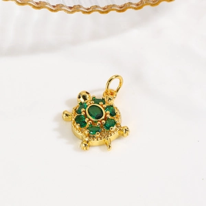 Detailed view of turtle charm with green crystals and 18k gold plated finish