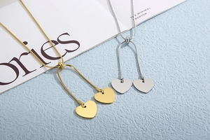Detail of adjustable gold and silver snake chain necklaces with twin heart pendants