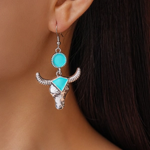 Detail of bohemian silver bull head earrings with teal enamel accents on a female model