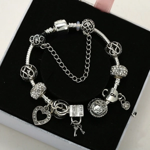 Detailed close-up of a silver-plated charm bracelet with heart and key pendants in a box
