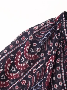 Detailed macro view of paisley print on dark blue chiffon blouse with pleat details