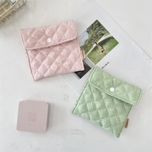 Close-up of quilted heart-shaped storage bags in pink and green with button closure