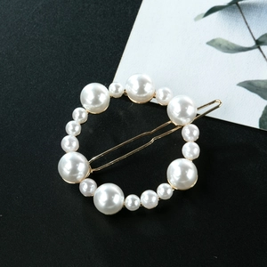 Close-up of golden irregular round hair clip with various sizes of white pearls