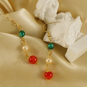 Détail de boucles d'oreilles 18k avec perles vertes, blanches et rouges sur soie dorée
