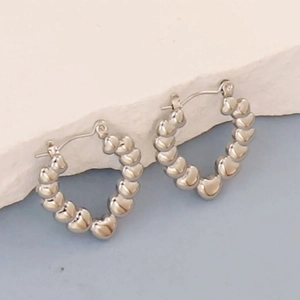 Detailed view of silver heart-shaped stainless steel hoop earrings with a polished finish