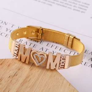 Detail of golden mesh watch-band bracelet with MOM heart pendant on wooden surface