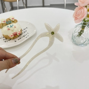 Détail d'un pic à cheveux en acétate blanc nacré orné d'une fleur en strass vert