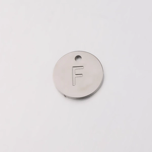 Close-up of 12mm mirror polished stainless steel round charm with letter F engraving