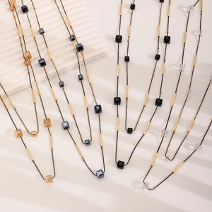 Detalle de collares de cristal geométricos para suéter con cuentas ámbar y oro