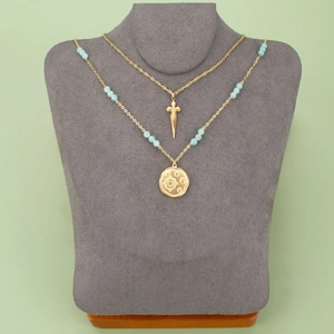 Layered gold necklaces with sunburst coin pendant, blue beads and sharp dagger charm