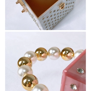 Detail of acrylic clutch bags with rhinestones and pearl bead handles in white and pink