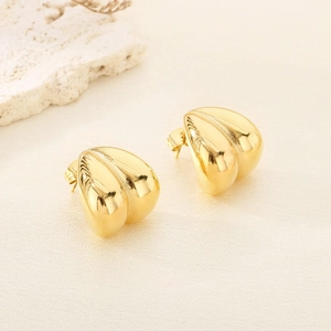 Détail des boucles d'oreilles en C plaqué or 18K en acier inoxydable sur fond textile