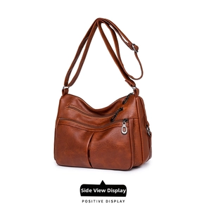 Detail of dark brown pebble leather crossbody bag with multiple zipper compartments