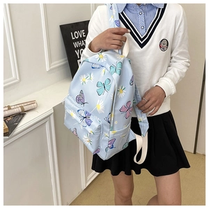 Detail of light blue backpack with colorful butterfly and daisy prints and white straps