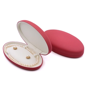 Red oval jewelry gift box set with white pearl necklace and earrings on white background
