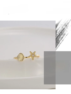 Detailansicht eines goldenen Rings mit Seestern, Muschel und Zirkonia-Inlay