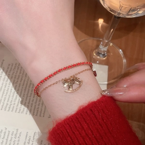 Detailed view of red woven string bracelet with a golden rocking horse pendant for women