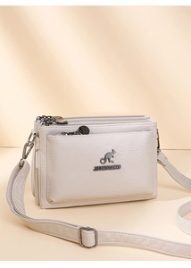 Vista de detalle del bolso bandolera beige de varias capas en piel sintética con cremalleras