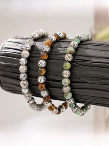 Detail of tiger eye, marble, and turquoise beaded bracelets on a black wooden stand