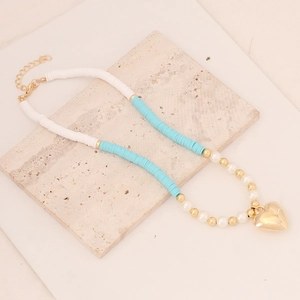 Bohemian handmade heishi bead necklace with pearls and gold heart pendant on stone
