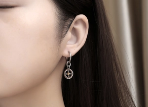 Close-up of men stainless steel hoop earring with a golden cross charm pendant