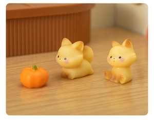 Macro detail of cute resin fox figurines and a small orange pumpkin for miniature decor