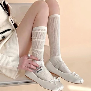 Detail von cremeweißen Shopper-Socken kombiniert mit weißen Ballerinas im College-Stil