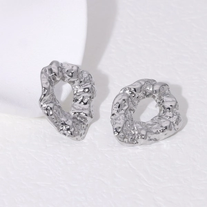 Macro detail of irregular lava texture on polished silver stainless steel stud earrings