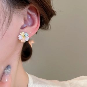 Close-up of 18k gold plated colorful acrylic flower stud earrings worn on the ear