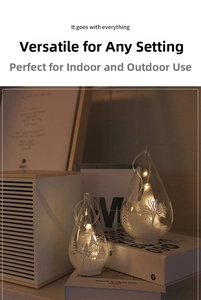 Glowing teardrop glass ornaments with warm LED lights and etched winter forest scenes