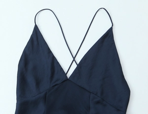 Detail eines dunkelblauen Satin-Kleides mit tiefem V-Ausschnitt und Spaghettiträgern