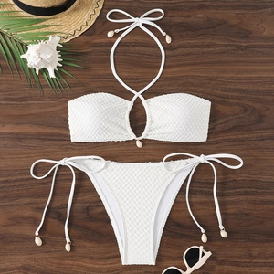 Close-up of white waffle texture bikini fabric with decorative seashell ties on wood
