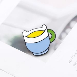 Detail view of a colorful enamel cup brooch on a paper background showing fine metal crafts