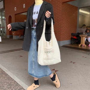 Nahaufnahme der weißen Plüschtasche mit Lucky-Stickerei und Smiley-Gesicht-Motiv