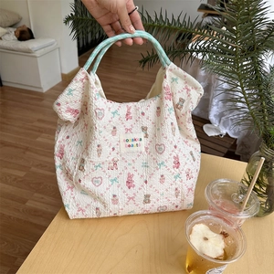 Detailed view of quilted cotton tote bag with cartoon bear and rabbit prints on a table