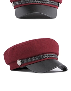 Detail of burgundy newsboy cap featuring black leather brim and silver metal buttons