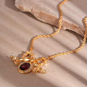 Macro shot of vintage gold bow necklace with oval red gemstone and zircon accents