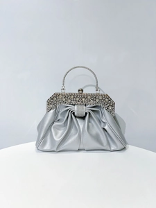 Detail of silver pleated evening bag with sparkling rhinestone handle and metal frame