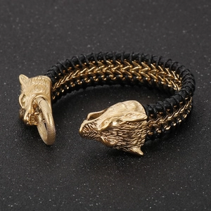 Detailed view of the golden wolf head clasp on a black braided leather bracelet for men