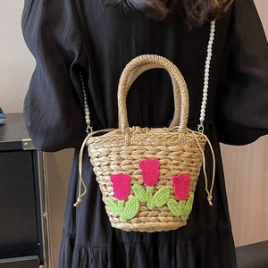Handgewebte Strohtasche mit rosa Tulpen und Perlenkette an einem Model gezeigt