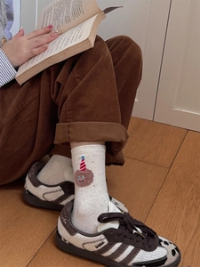 Detail of cream cotton sock with cute plush bear embroidery in a cozy lifestyle setting