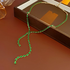 Detailed view of gold Y-shaped necklace featuring vibrant green stones and adjustable chain