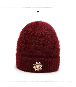 Front view of a burgundy knit hat for women featuring a golden floral faux pearl detail