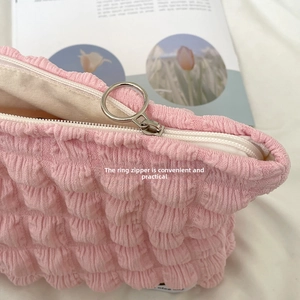 Detail of pink bubble gauze makeup bag featuring a smooth silver circular ring zipper puller