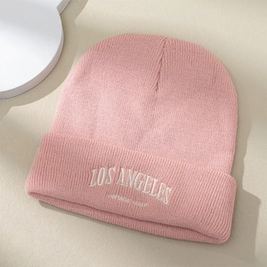 Bonnet en tricot rose avec broderie blanche Los Angeles sur une surface beige chic