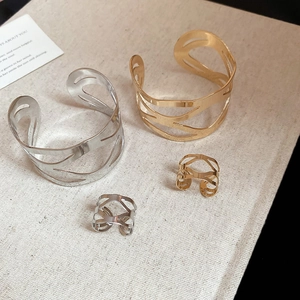 Detail of hollow geometric wavy jewelry set featuring gold and silver bangles and rings