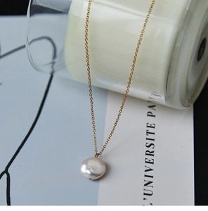 Macro-detail van een zoetwater parelhanger aan een dunne 18K vergulde ketting