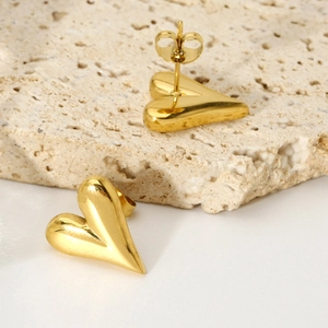 Detailed view of heart-shaped gold-plated stainless steel earrings on a stone surface