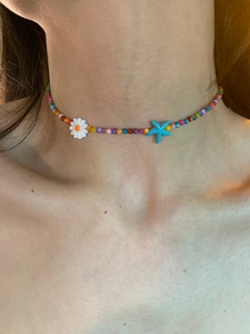 Close-up of colorful beaded necklace with white daisy and blue starfish resin charms