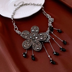 Vue détaillée du collier fleur avec strass noirs et pompons en pierres précieuses